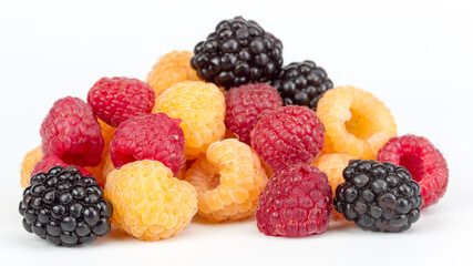 Lot of organic red and yellow raspberries and black blackberries on white background. Selective focus