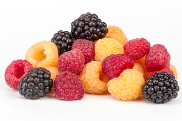 Lot of organic red and yellow raspberries and black blackberries on white background. Selective focus
