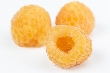 Lot of organic yellow raspberries on white background. Selective focus