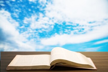 Holy Bible book on a wooden desk and sky background