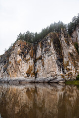 Fototapeta na wymiar rock going into the river, stone cliff, morning on the river, fog, landscape in cloudy weather, Russia southern Urals Yuryuzan river, nature of Russia