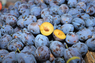 Pile of fresh prunes and one plum cut in a half.