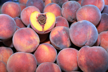 A pile of peaches and one peach, cut in half