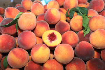 A pile of peaches and one peach, cut in half