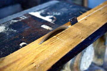Cutting a wooden Board on a circular sawmill by a person