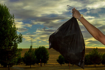 Image of the hands of a Caucasian woman collecting plastic garbage in a meadow