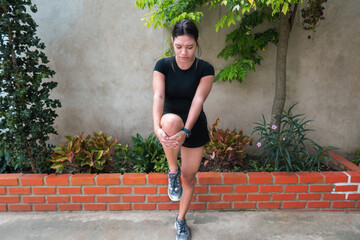 Running injury - Woman running with knee pain. Close-up of an injured jogger running in the park holding on to his knee in pain. Female fitness athlete.