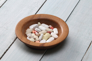 tablets and capsule in a wooden bowl.