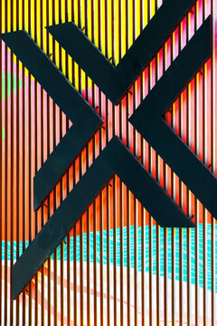 Three-dimensional form of an X attached to colorful painted panels