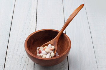 tablets and capsule in a wooden bowl.