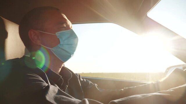 worker driver wearing medical mask drives a car during the coronavirus period. delivery during the pandemic parcel concept. male wearing a mask driver protection taxi against coronavirus