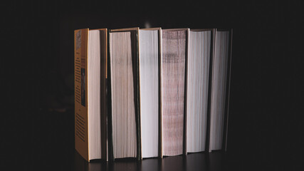 High messy stack of books on a black background with space for text message.