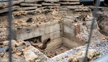 Insulated pipes and concrete slabs in trench outdoors.