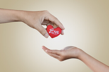 Red heart in father and child girl hands. Concept of love, giving gifts, donorship.