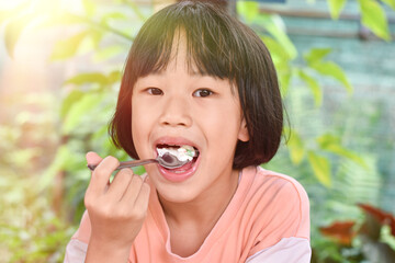 Fototapeta premium Close-up of Child girl hands holding spoon eating ice cream. Selective focus