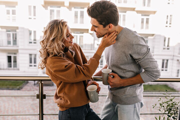 Laughing fair-haired woman posing at terrace with cup of coffee. Portrait of smiling caucasian girl...