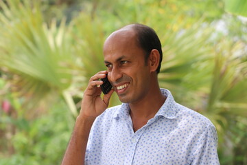 Casual dressed smiling Asian man talking on mobile phone