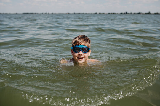 Teenager Boy Wearing Goggles Swimming In A Lake. Summer Vacation Time