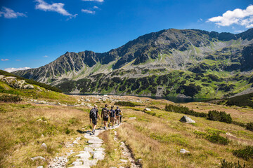Group of hikers walks through the valley in the High Mountains. Alpine style landscape in the summer. Tourism in outdoors. Beautifull landscape in Poland.	
