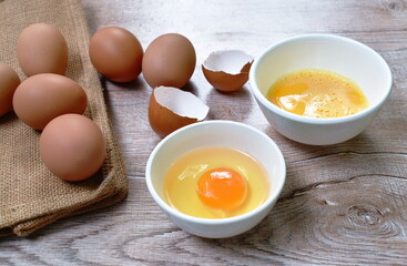 raw egg yolk in cup and crack brown shell on table