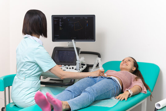 Doctor holds an ultrasound scanner in his hand and makes an ultrasound diagnosis of the abdominal cavity to the female patient. Medical research close up.