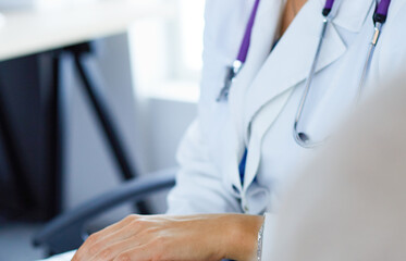 Woman doctor helping senior holding hand in hospital