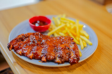 half rack of barbecue pork ribs with french fries on plate with very thing selective focus