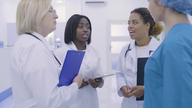 Afro-american chief doctor delegating tasks to colleagues, teamwork in hospital