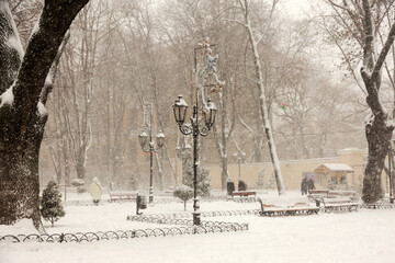 Winter city landscape. People on the streets of the city during snowfall.