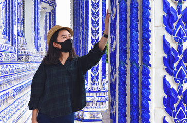 A new kind of travel woman wearing a mask and sightseeing in a temple in Thailand.