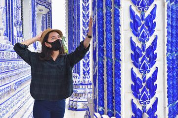 Happy traveler asian woman with face mask and sightseeing in Temple, Thailand