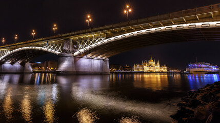 Naklejka na ściany i meble Panorama view of Budapest. Margaret bridge and Parliament building in Budapest at night, with reflection in calm water Danube river, Hungary
