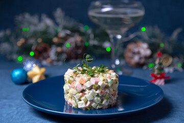Olivier salad on a blue plate, decorated with pea sprouts. Traditional New Year and Christmas Russian salad.