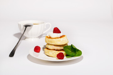Delicious and healthy cheesecakes with sour cream and raspberries, with a Cup of black coffee. 