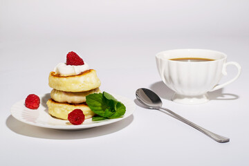 Delicious and healthy cheesecakes with sour cream and raspberries, with a Cup of black coffee. 