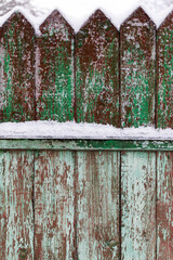Texture of weathered wooden wall. Falling snow, in winter. Aged wooden plank fence of vertical flat boards