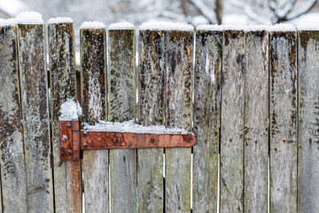 Texture of weathered wooden wall. Falling snow, in winter. Aged wooden plank fence of vertical flat boards