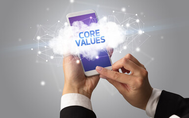 Female hand touching smartphone with CORE VALUES inscription, cloud business concept