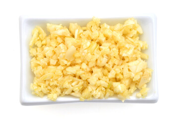 Sliced garlic in white bowl on white background