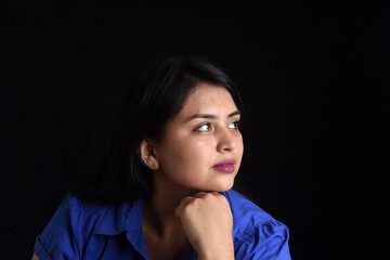 portrait of a latin woman looking to the side on black background,  hand on chin