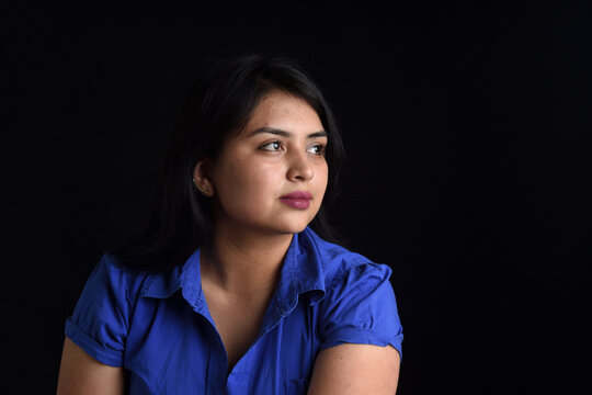 portrait of a latin woman looking to the side on black background