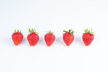 five strawberry berries in a row on a white background