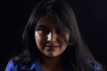 dark portrait of a latin woman on black background, smile