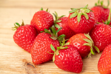 a lot of fresh strawberries on the wooden table are taken off the side