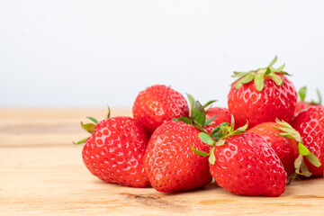 a lot of fresh strawberries on the wooden table are taken off the side