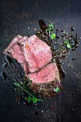 Traditional barbecue dry aged wagyu chateaubriand beef steak offerd spice and herbs as top view on a rustic metal board