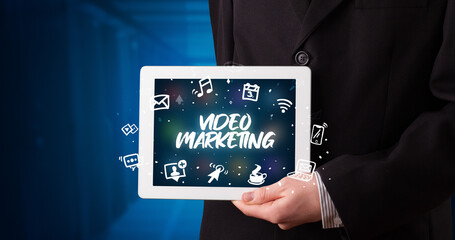 Young business person working on tablet and shows the inscription: VIDEO MARKETING