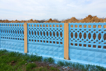 Long blue concrete fence near rural house