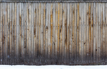 The texture of weathered wooden wall. Aged wooden plank fence of vertical flat boards