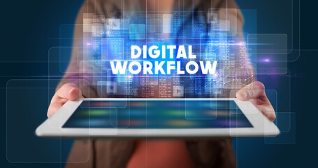 Young business person working on tablet and shows the inscription: DIGITAL WORKFLOW